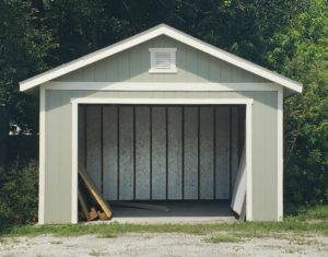 A 12 by 12 foot grey garage stands open and empty except for some wooden pallets.